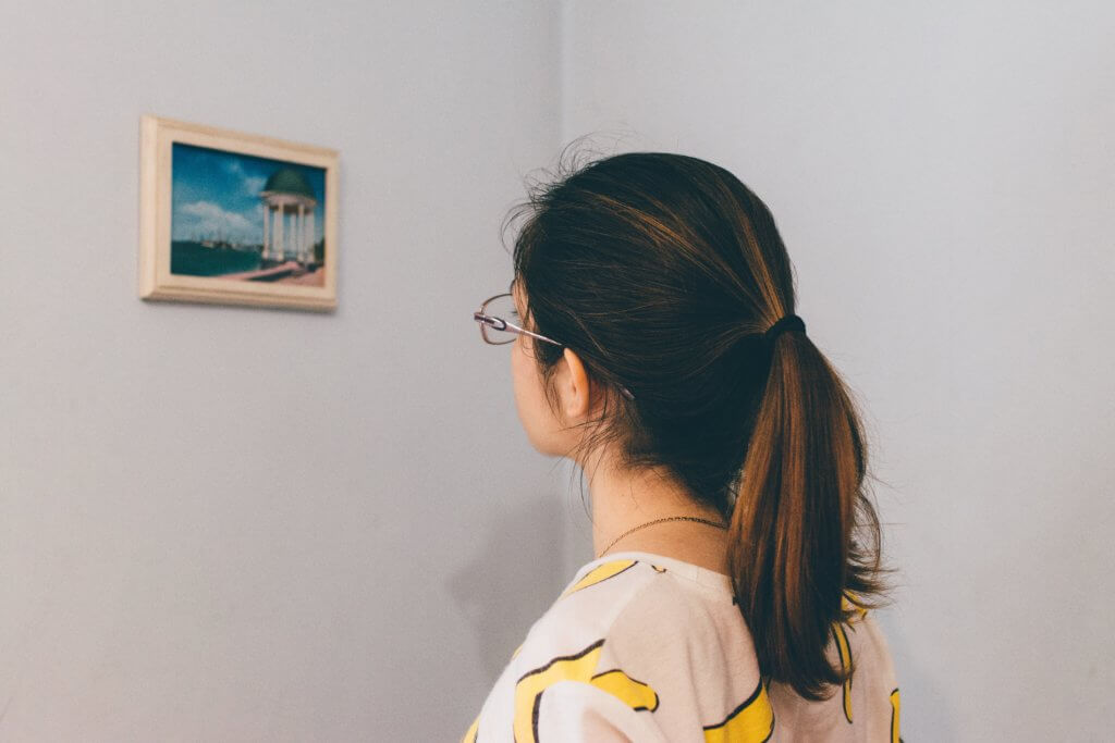 Women looking at a small framed painting on a wall